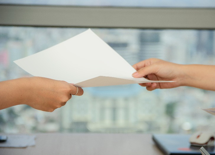 A sheet of paper among two hands. Photo: pexels.com
