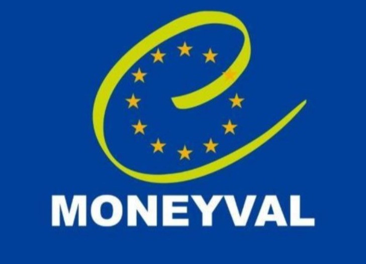 Moneyval logo: uz tumši zila fona dzeltenas zvaigznes aplī, kam pāri pārvilkts e burts. Apakšā teksts Moneyval. 