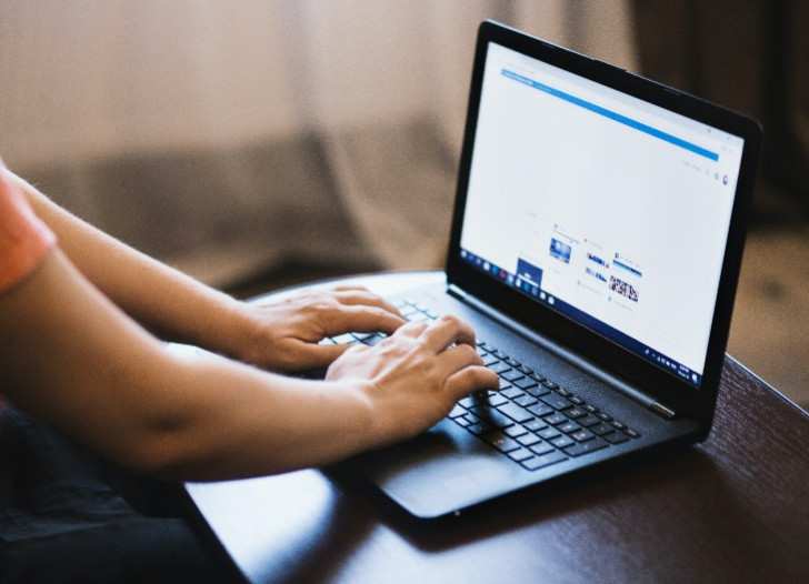 Persona drukā uz portatīvā datora. Foto: pexels.com